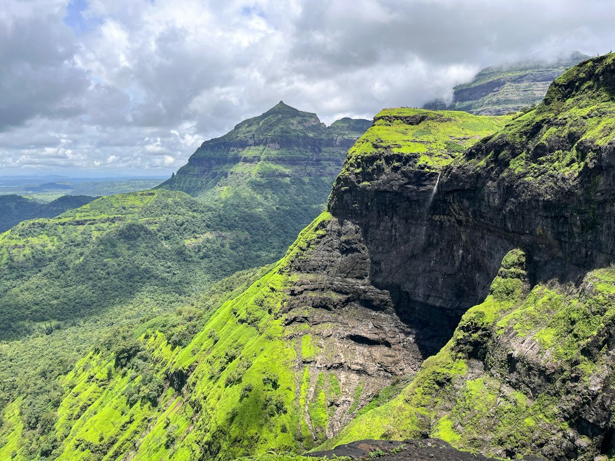 Green Sahyadri cliffs and valleys under a cloudy sky