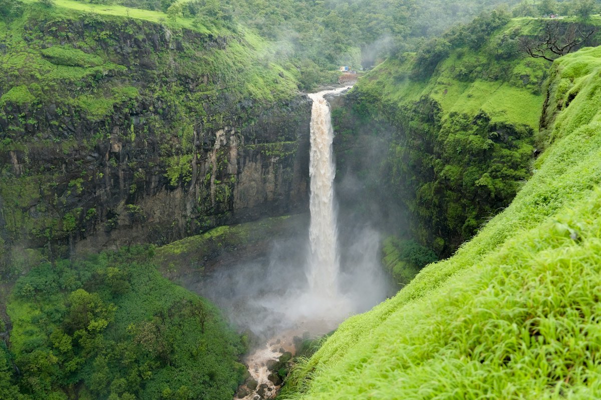 A tall waterfall plunging into a lush green valley